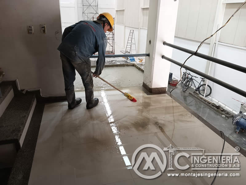 Acabado y curado de piso de concreto en mezzanine industrial en Bogotá, Colombia.