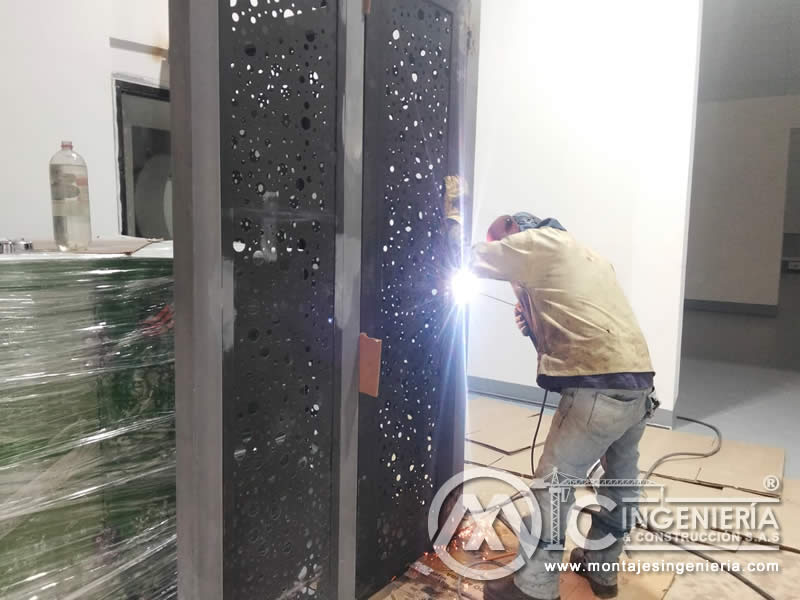 Proceso de soldadura en divisiones metálicas con paneles perforados en Bogotá, Colombia. Montajes, Ingeniería y Construcción MIC SAS.