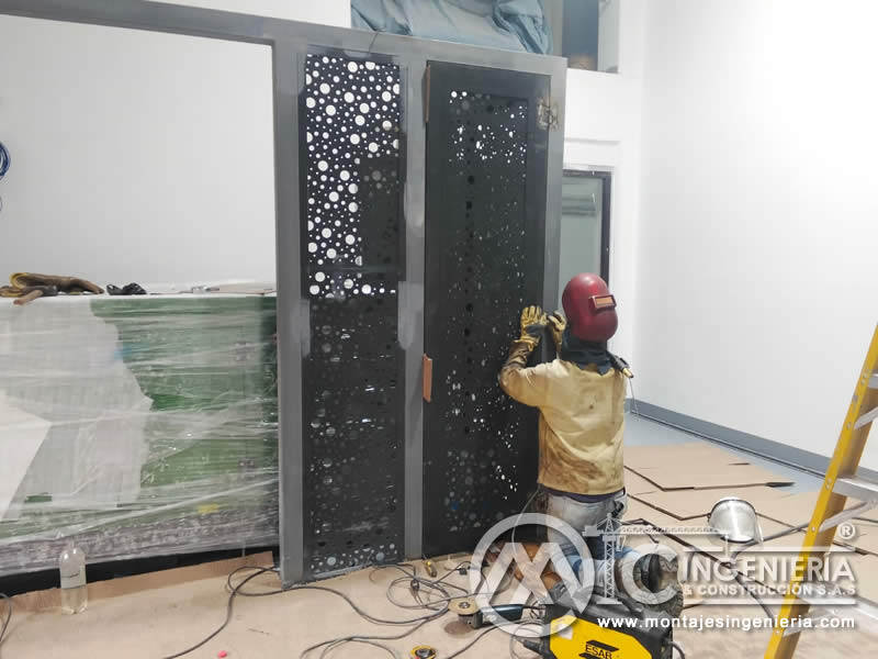 Soldadura de puertas metálicas con paneles perforados en espacios interiores en Bogotá, Colombia. Montajes, Ingeniería y Construcción MIC SAS.