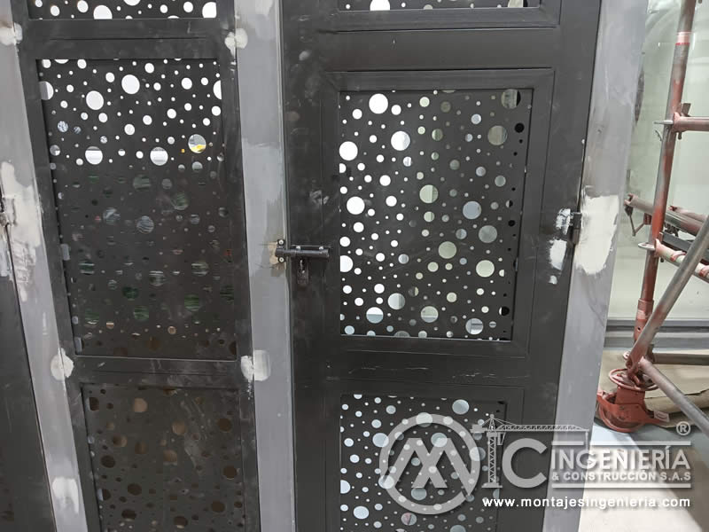 Ajuste de herrajes y bisagras en puertas metálicas perforadas para locales comerciales en Bogotá, Colombia. Montajes, Ingeniería y Construcción MIC SAS.