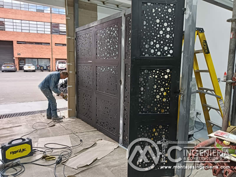 Fijación de portones metálicos perforados en acceso de local comercial con soldadura en Bogotá, Colombia. Montajes, Ingeniería y Construcción MIC SAS.