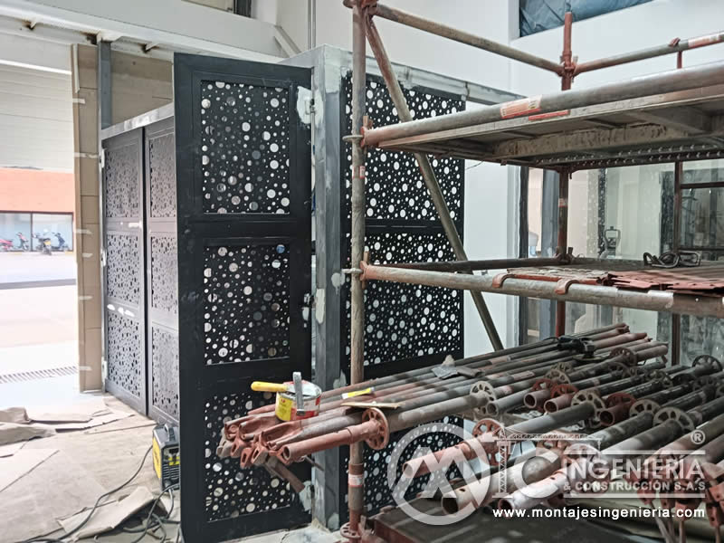 Instalación de portones metálicos perforados con apoyo de andamios tubulares en local comercial en Bogotá, Colombia. Montajes, Ingeniería y Construcción MIC SAS.
