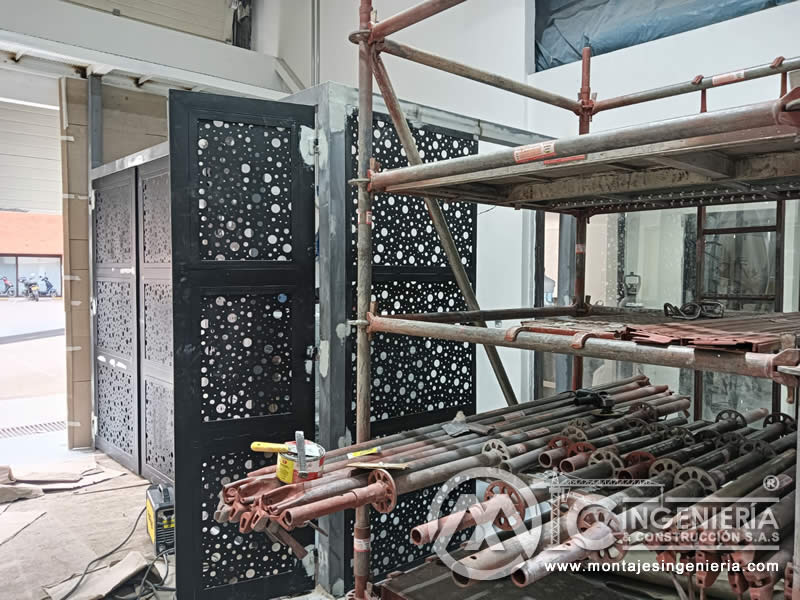 Montaje de puertas metálicas perforadas con apoyo de andamios en local comercial en Bogotá, Colombia. Montajes, Ingeniería y Construcción MIC SAS.