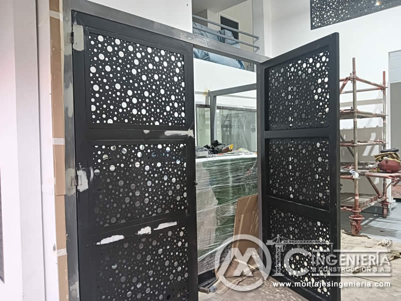 Portones decorativos de lámina perforada abiertos en acceso de local comercial en Bogotá, Colombia. Montajes, Ingeniería y Construcción MIC SAS.