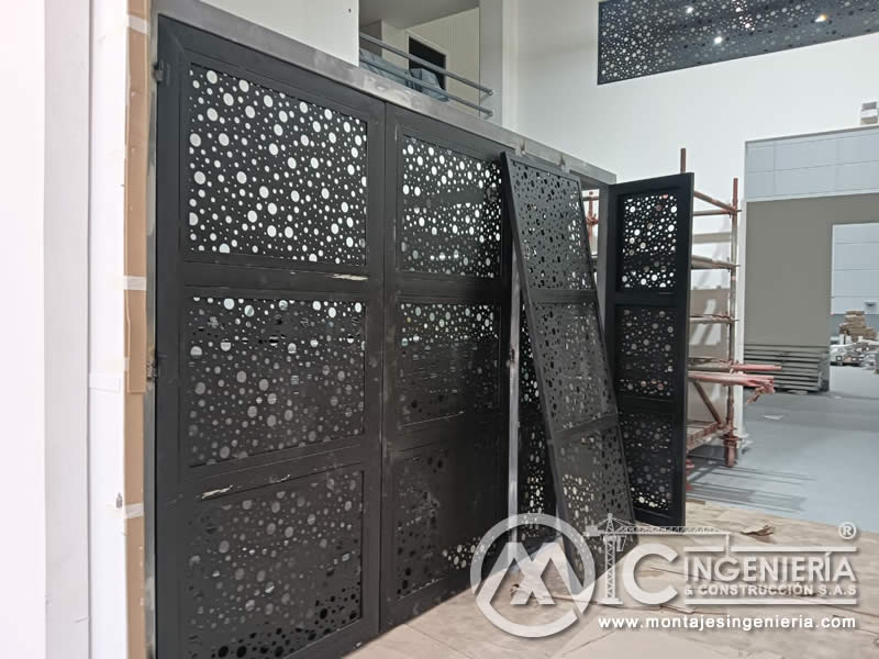 Portones metálicos decorativos con lámina perforada instalados en acceso de local comercial en Bogotá, Colombia. Montajes, Ingeniería y Construcción MIC SAS.