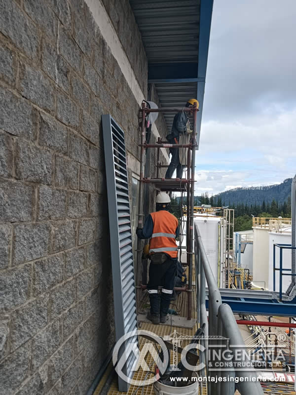 Dos técnicos instalando louver metálico en fachada industrial en Bogotá, Colombia. Montajes, Ingeniería y Construcción MIC SAS.