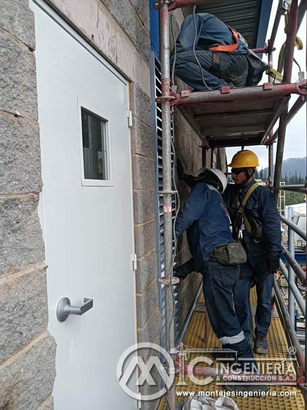 Instalación de puerta metálica en fachada de planta industrial en Bogotá, Colombia. Montajes, Ingeniería y Construcción MIC SAS.