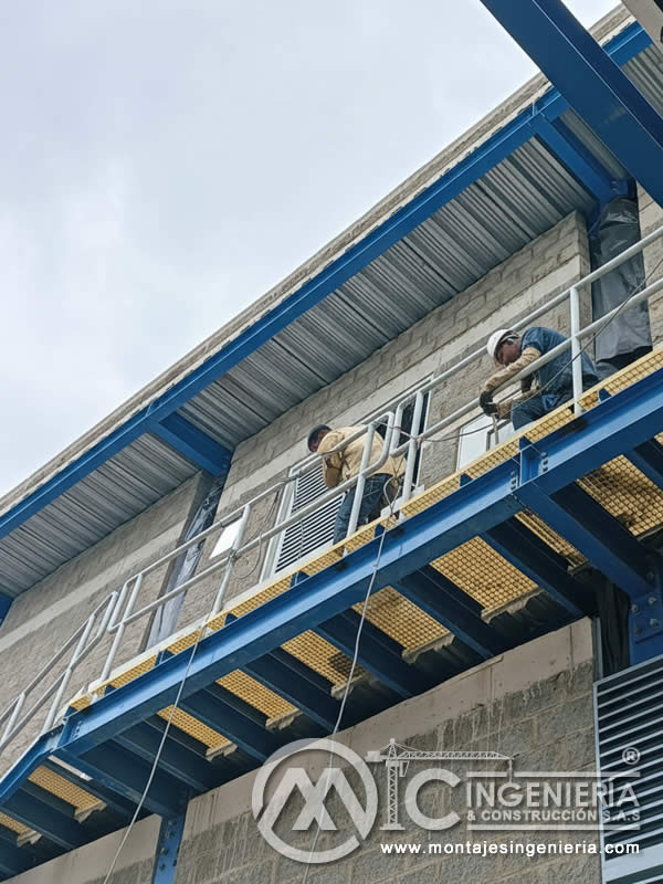 Operarios instalando rejilla FRP en plataforma metálica de planta industrial en Bogotá, Colombia. Montajes, Ingeniería y Construcción MIC SAS.