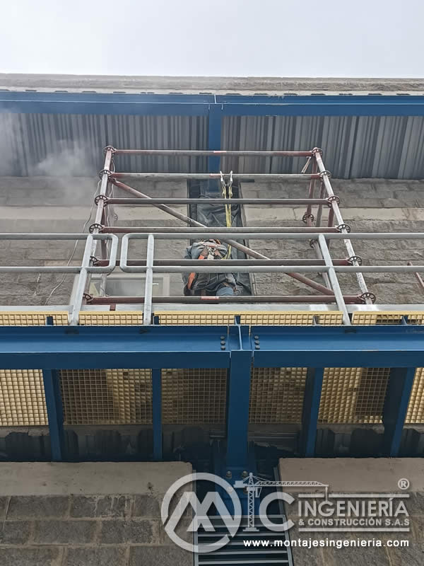 Plataforma metálica azul con rejilla FRP vista desde abajo en planta industrial en Bogotá, Colombia. Montajes, Ingeniería y Construcción MIC SAS.