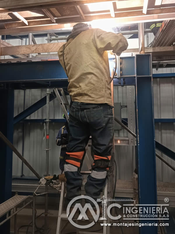 Soldadura de estructuras metálicas azules en interior de planta industrial en Bogotá, Colombia. Montajes, Ingeniería y Construcción MIC SAS.