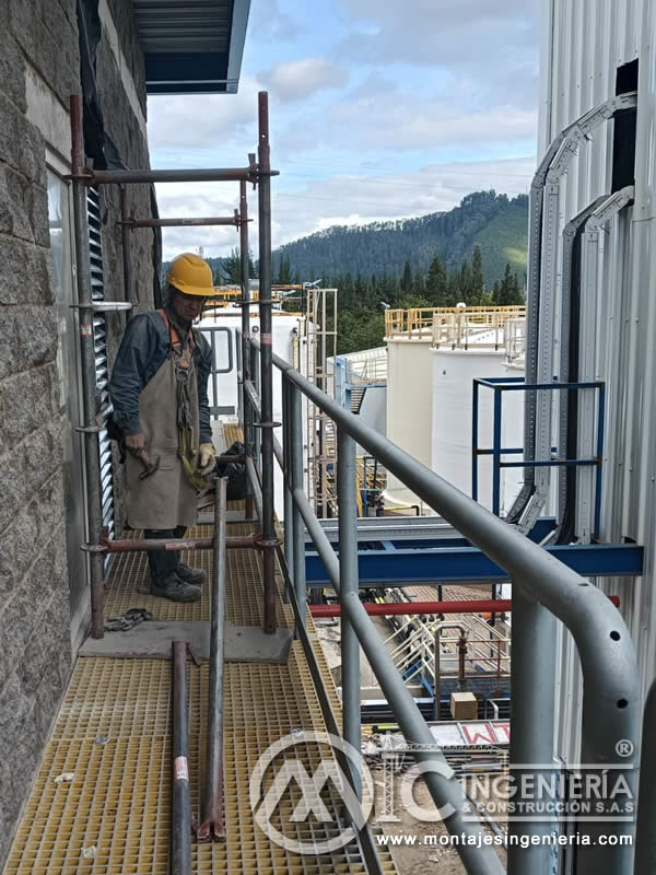Técnico en plataforma FRP con andamio en fachada de planta industrial en Bogotá, Colombia. Montajes, Ingeniería y Construcción MIC SAS.