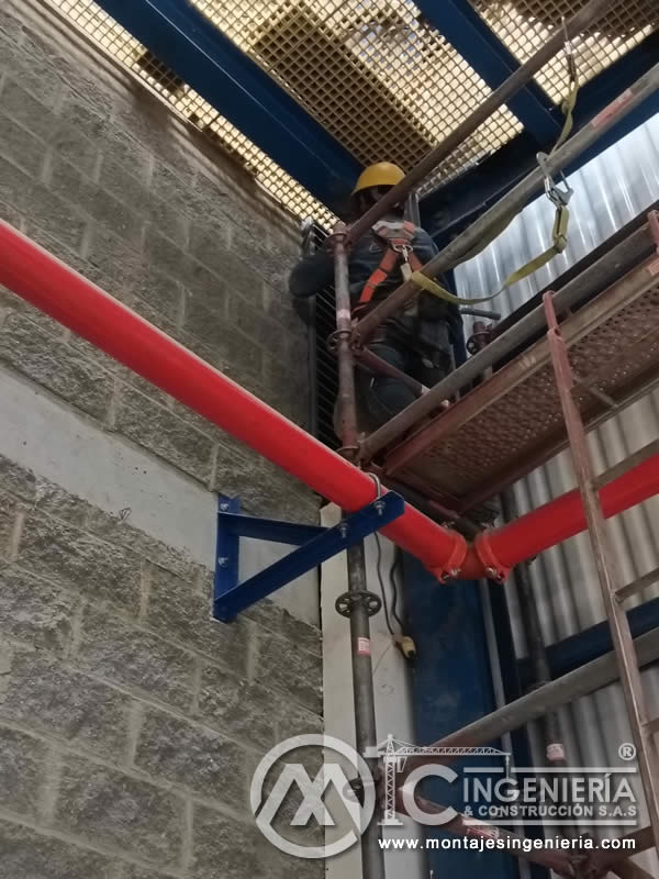 Instalación de tuberías pintadas con soportes en muros industriales en Bogotá, Colombia. Montajes, Ingeniería y Construcción MIC SAS.