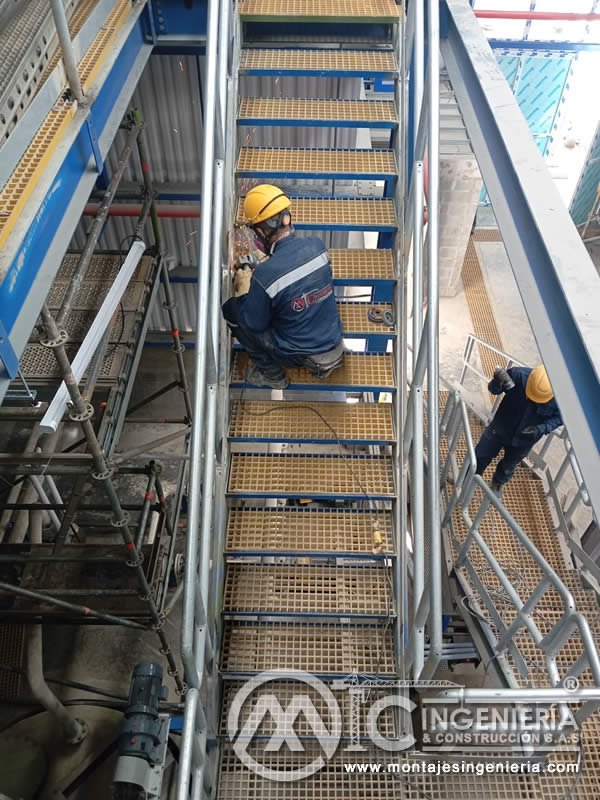 Ajuste de peldaños en escalera metálica industrial con rejilla plástica en planta de producción en Bogotá, Colombia. Montajes, Ingeniería y Construcción MIC SAS.