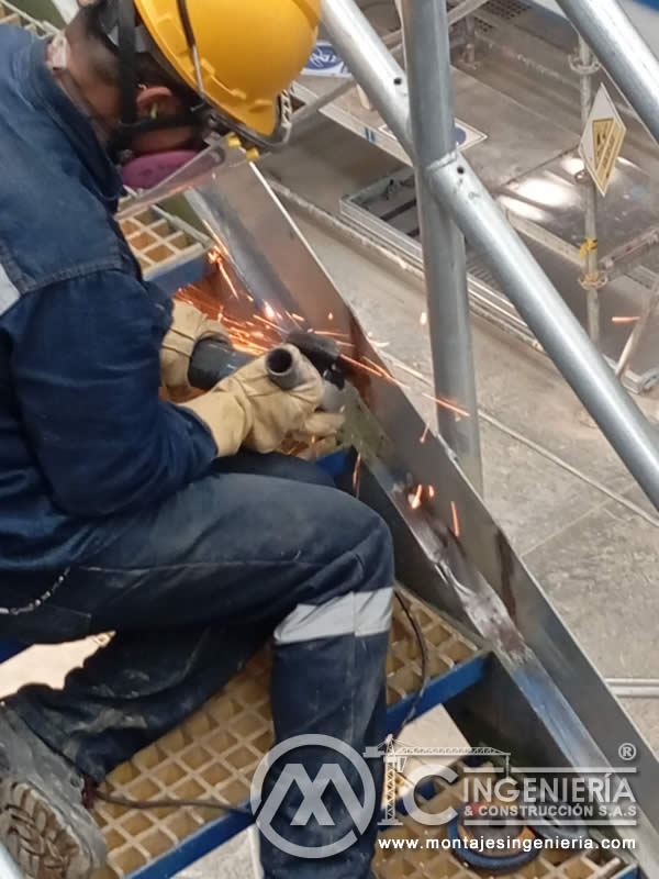 Corte con amoladora de perfiles metálicos en trabajo en altura sobre andamios industriales en Bogotá, Colombia. Montajes, Ingeniería y Construcción MIC SAS.