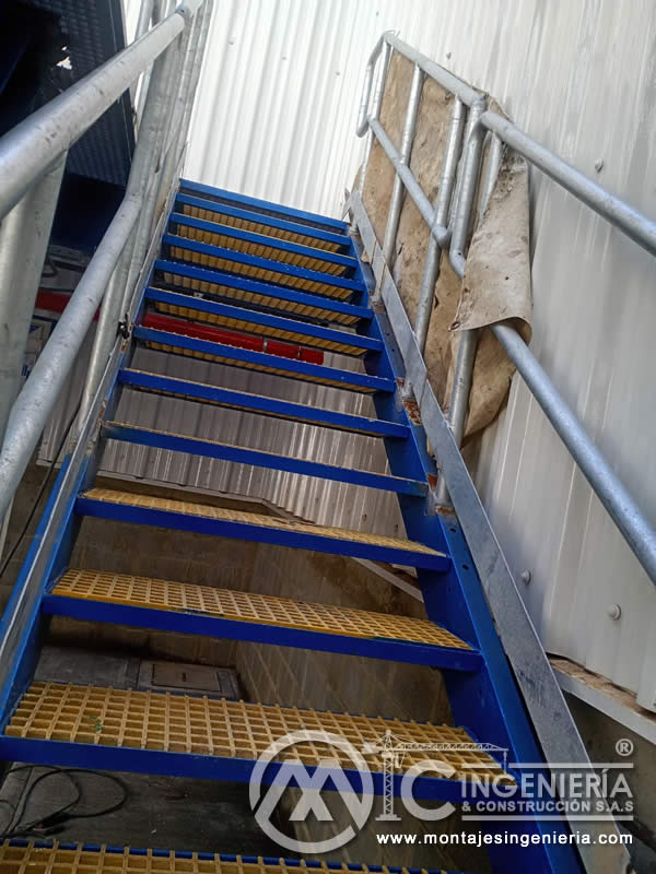 Escalera industrial pintada en azul con peldaños de rejilla antideslizante para bodegas en Bogotá, Colombia. Montajes, Ingeniería y Construcción MIC SAS.