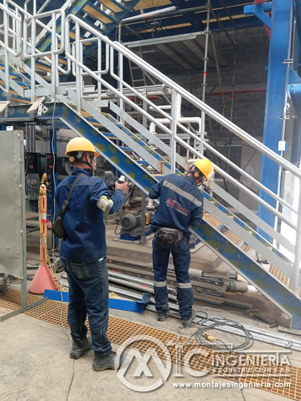 Instalación de motorreductor en planta industrial con escalera metálica y piso de rejilla en Bogotá, Colombia. Montajes, Ingeniería y Construcción MIC SAS.