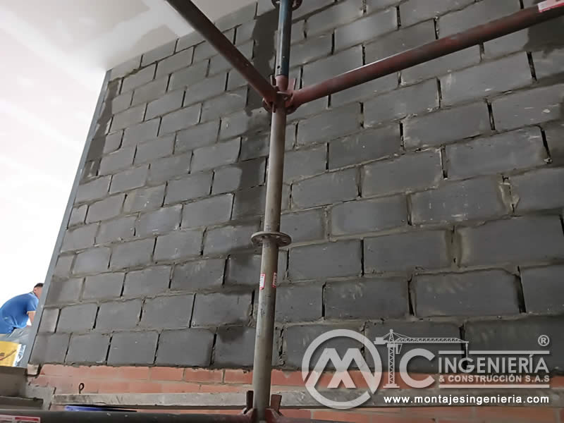 Levantamiento de muros en bloque gris de concreto con andamio tubular para obras de construcción en Bogotá, Colombia. Montajes, Ingeniería y Construcción MIC SAS.