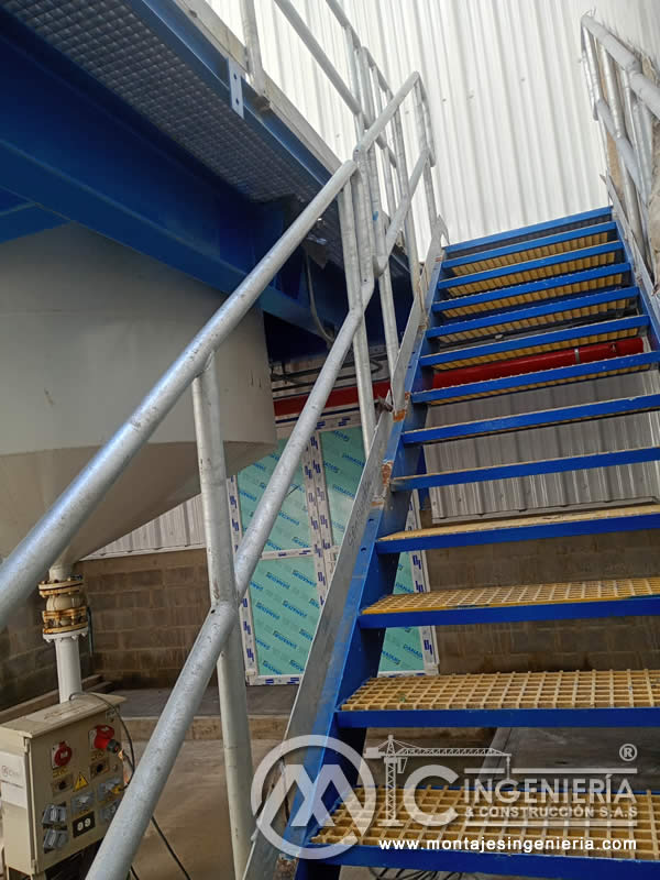 Montaje de escalera con pasamanos tubular galvanizado y peldaños de rejilla para planta industrial en Bogotá, Colombia. Montajes, Ingeniería y Construcción MIC SAS.