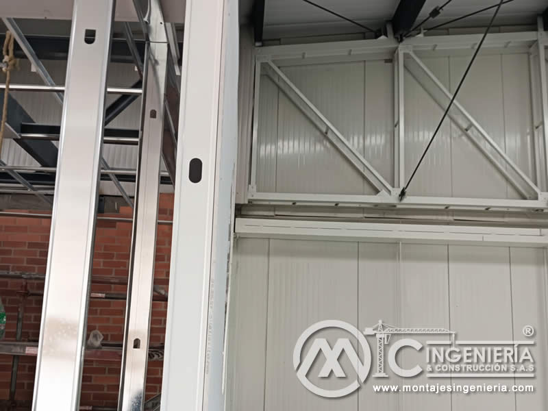 Montaje de puerta metálica seccional con estructura en acero para bodegas industriales en Bogotá, Colombia. Montajes, Ingeniería y Construcción MIC SAS.