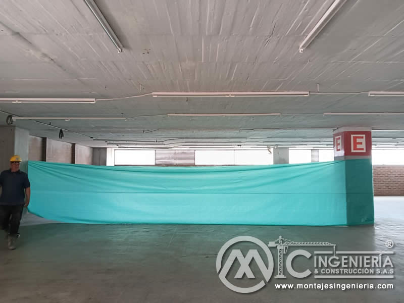 Instalación de plástico protector en parqueadero cubierto antes de trabajos de pintura en Bogotá, Colombia. Montajes, Ingeniería y Construcción MIC SAS.