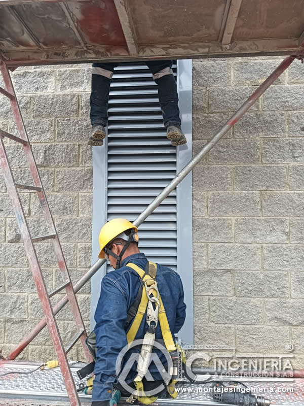 Instalación de rejillas con lamas en muros industriales con arnés de seguridad en Bogotá, Colombia. Montajes, Ingeniería y Construcción MIC SAS.