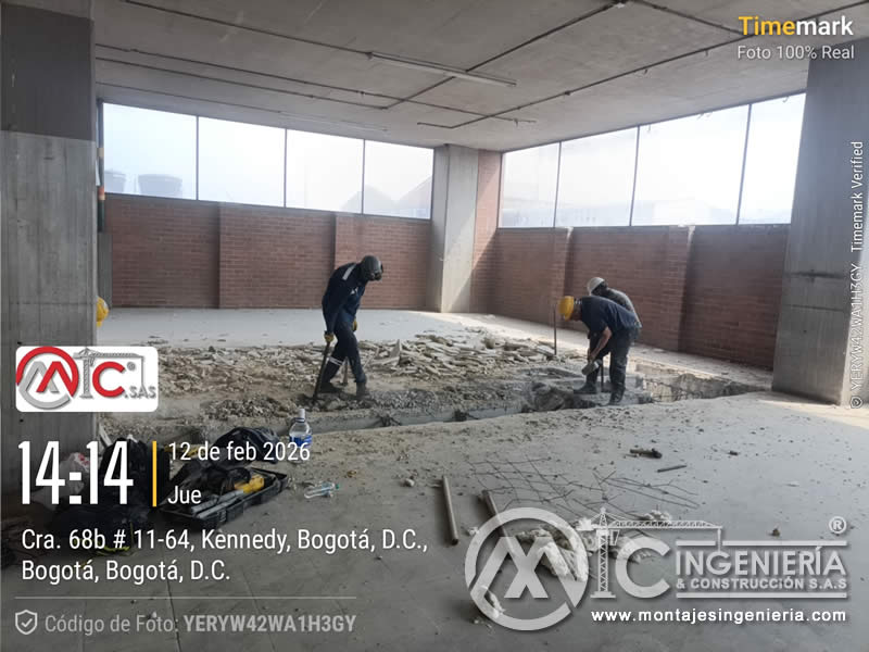 Operarios en demolición de placa de piso en parqueadero de edificio para nueva cimentación en Bogotá, Colombia. Montajes, Ingeniería y Construcción MIC SAS.