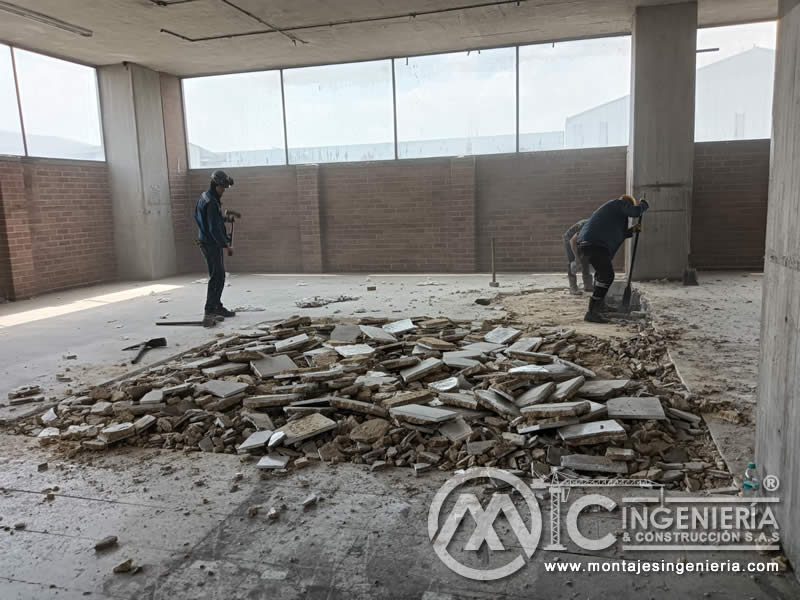Operarios en retiro de escombros de enchape de piso en parqueadero interior en Bogotá, Colombia. Montajes, Ingeniería y Construcción MIC SAS.
