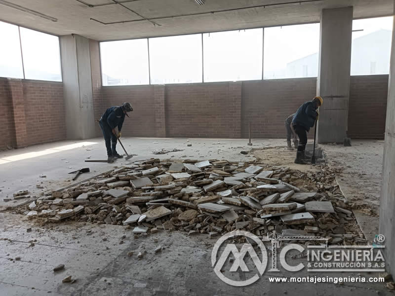 Recolección de escombros de piso en nave de parqueadero tras demolición de enchape en Bogotá, Colombia. Montajes, Ingeniería y Construcción MIC SAS.