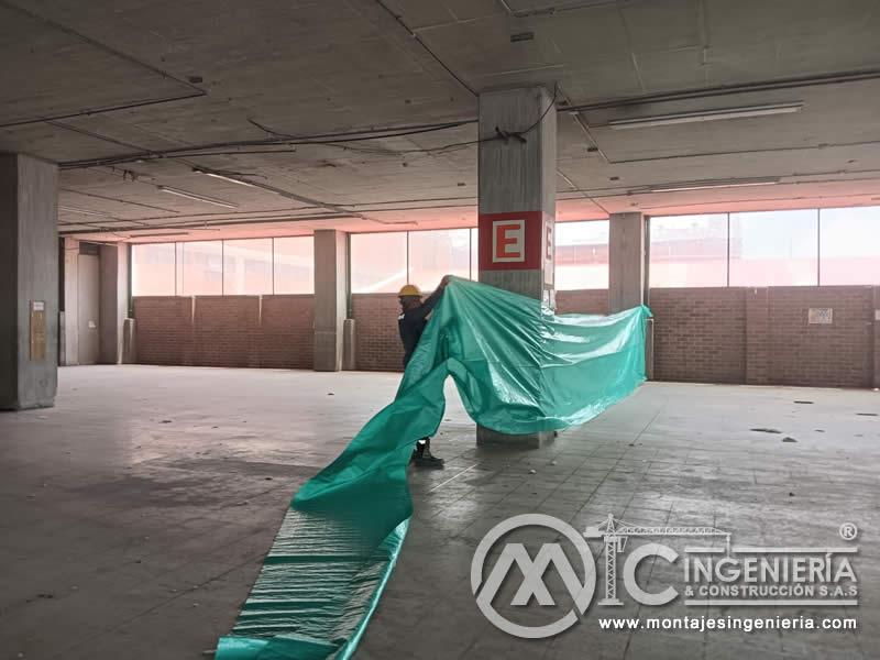 Retiro de plástico protector en parqueadero cubierto tras finalización de acabados en Bogotá, Colombia. Montajes, Ingeniería y Construcción MIC SAS.