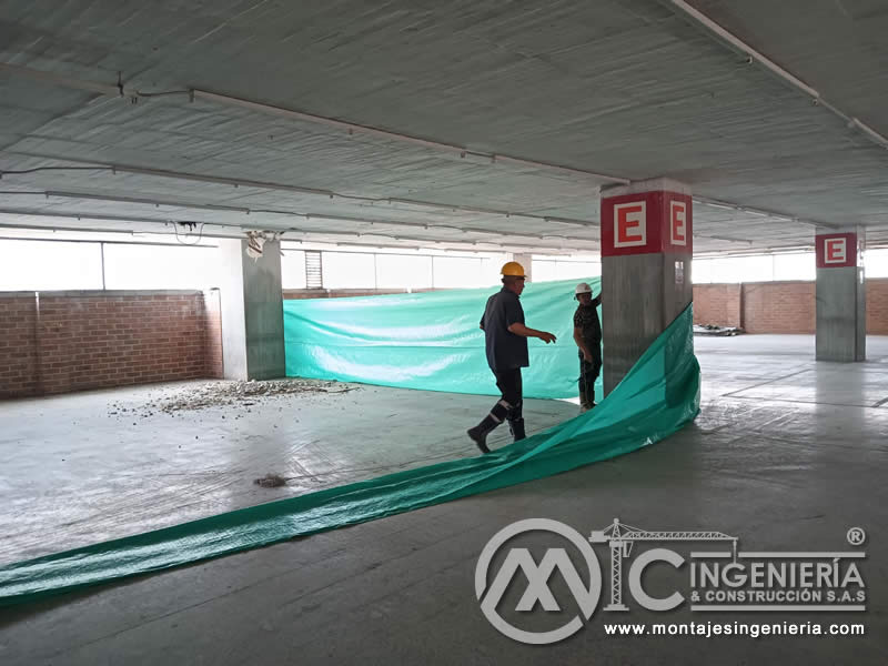Tendido de plástico protector en piso de parqueadero cubierto para adecuación en Bogotá, Colombia. Montajes, Ingeniería y Construcción MIC SAS.