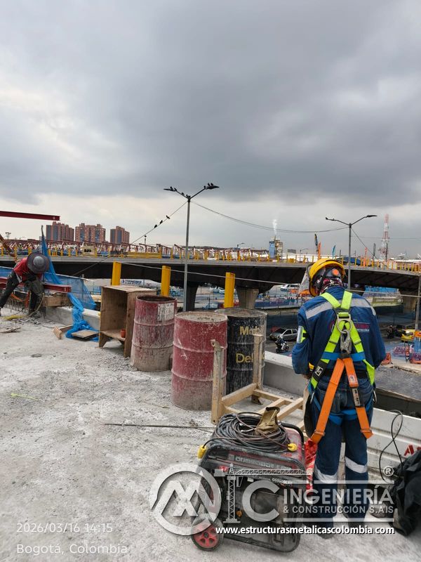 Trabajador con arnés junto a materiales de barandas amarillas del puente Venecia con fabricación e instalación profesional en Bogotá, Colombia. Montajes, Ingeniería y Construcción. MIC SAS. Trabajador con arnés junto a materiales de barandas amarillas del puente Venecia en Bogotá, Colombia. Montajes, Ingeniería y Construcción. MIC SAS.