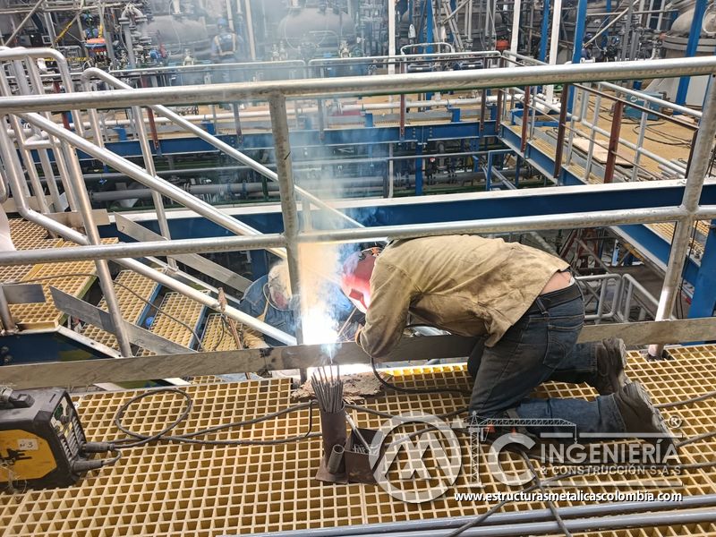 Trabajador soldando piso de rejilla sobre pasarela industrial del Edificio eléctrico CCM - Brinsa con fabricación e instalación profesional en Bogotá, Colombia. Montajes, Ingeniería y Construcción. MIC SAS. Trabajador soldando piso de rejilla sobre pasarela industrial del Edificio eléctrico CCM - Brinsa en Bogotá, Colombia. Montajes, Ingeniería y Construcción. MIC SAS.