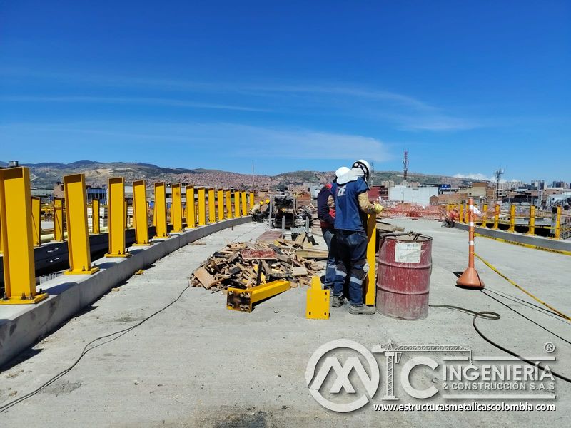 Admire la cuadrilla ajustando un poste tubular para mantener firme la protección lateral del puente hoy en Bogotá, Colombia. Montajes, Ingeniería y Construcción. MIC SAS.