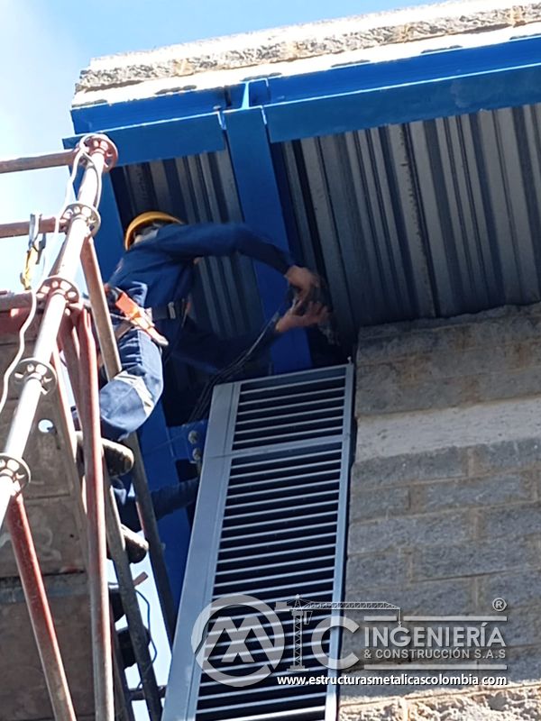 Trabajador instalando persiana vertical desde escalera y andamio del Edificio eléctrico CCM - Brinsa en Bogotá, Colombia. Montajes, Ingeniería y Construcción. MIC SAS.