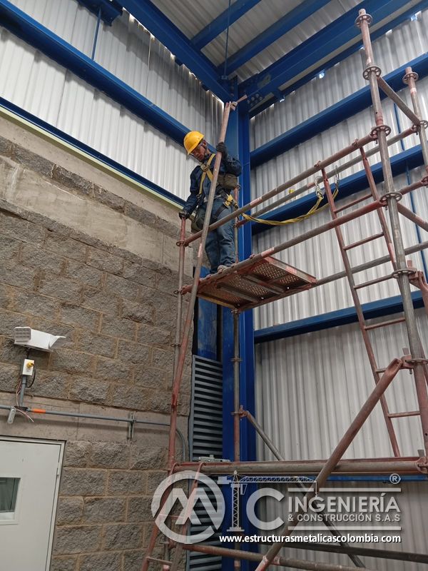 Trabajador instalando persiana vertical desde escalera y andamio del Edificio eléctrico CCM - Brinsa en Bogotá, Colombia. Montajes, Ingeniería y Construcción. MIC SAS.