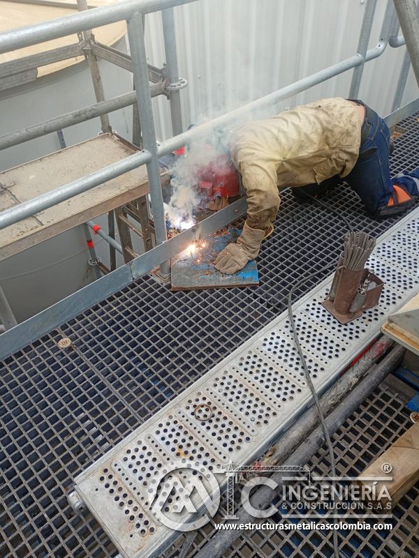 Trabajador soldando piso de rejilla en plataforma del Edificio eléctrico CCM - Brinsa en Bogotá, Colombia. Montajes, Ingeniería y Construcción. MIC SAS.