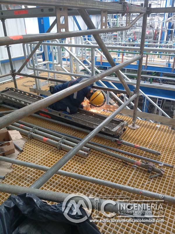 Trabajador ajustando baranda junto a piso de rejilla del Edificio eléctrico CCM - Brinsa en Bogotá, Colombia. Montajes, Ingeniería y Construcción. MIC SAS.