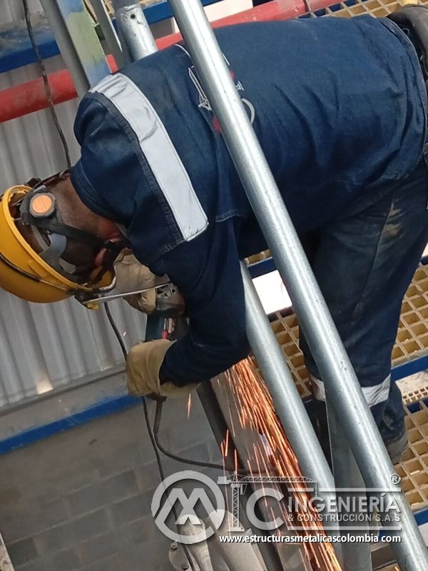 Trabajador ajustando baranda junto a escalera y piso de rejilla del Edificio eléctrico CCM - Brinsa en Bogotá, Colombia. Montajes, Ingeniería y Construcción. MIC SAS.
