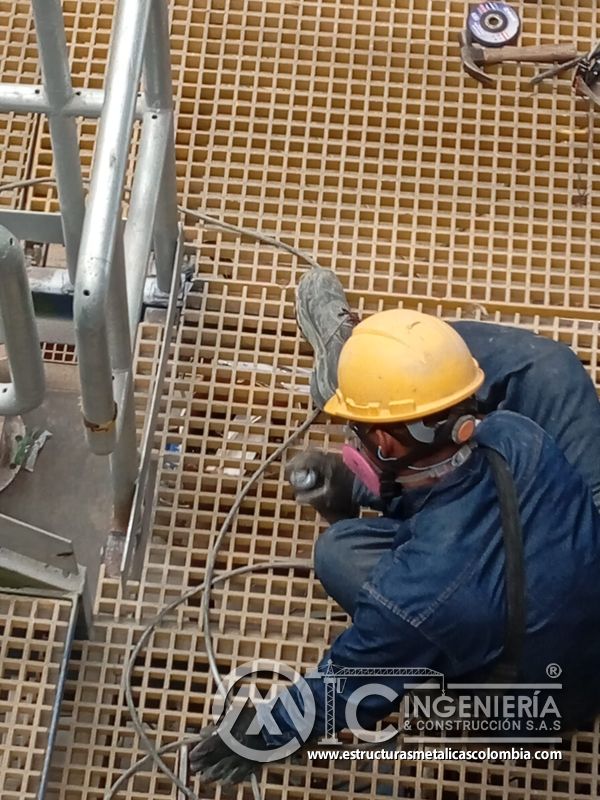 Trabajador sobre piso de rejilla en escalera industrial del Edificio eléctrico CCM - Brinsa en Bogotá, Colombia. Montajes, Ingeniería y Construcción. MIC SAS.