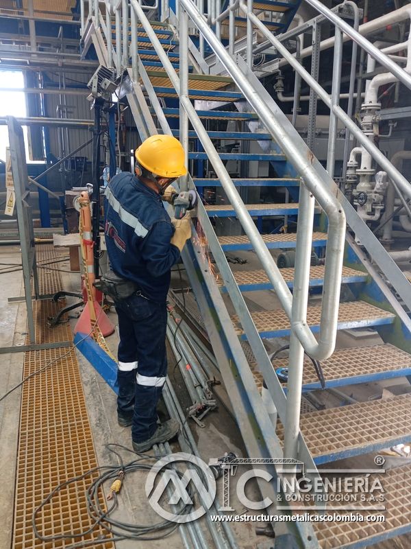 Trabajador sobre piso de rejilla en escalera industrial del Edificio eléctrico CCM - Brinsa en Bogotá, Colombia. Montajes, Ingeniería y Construcción. MIC SAS.