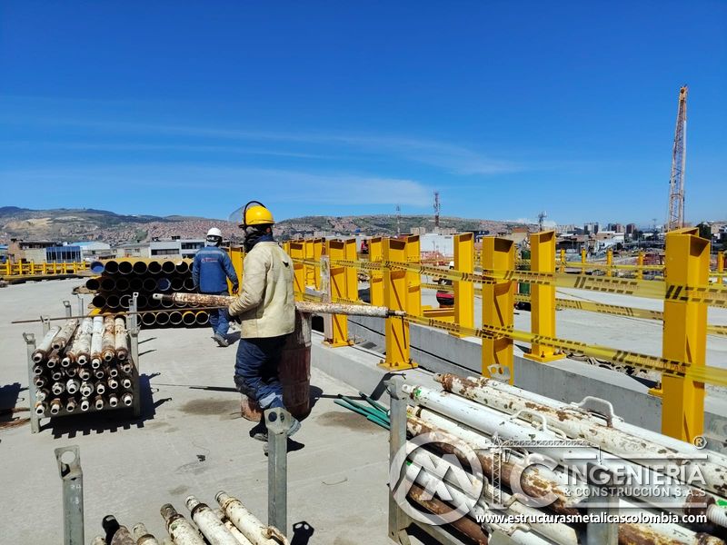 Constate obreros movilizando una tubería entre andamios y soportes para continuar la baranda del puente en Bogotá, Colombia. Montajes, Ingeniería y Construcción. MIC SAS.