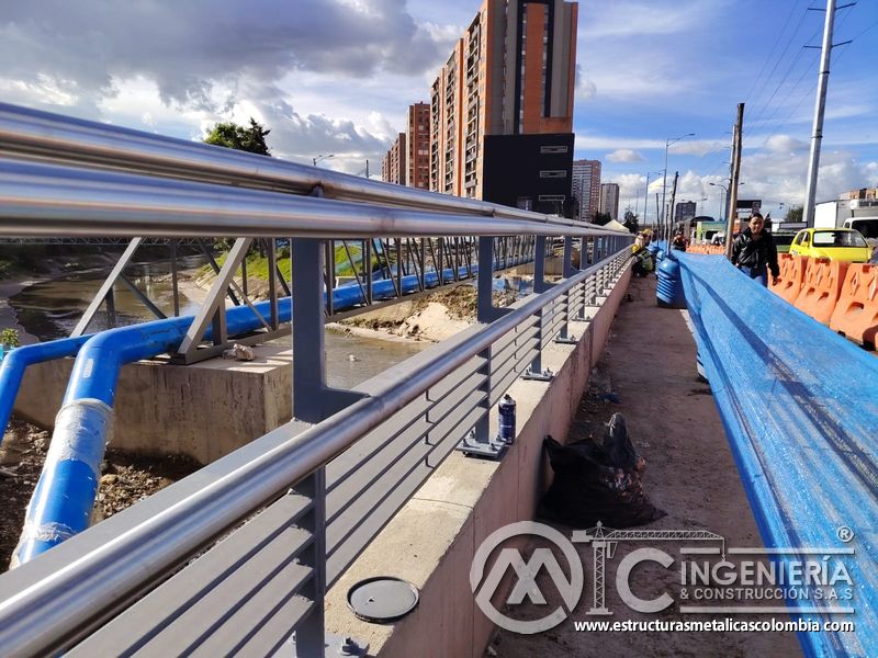 Valore la alineación de pasamanos pulidos sobre postes grises fijados al concreto junto al cauce urbano en Bogotá, Colombia. Montajes, Ingeniería y Construcción. MIC SAS.