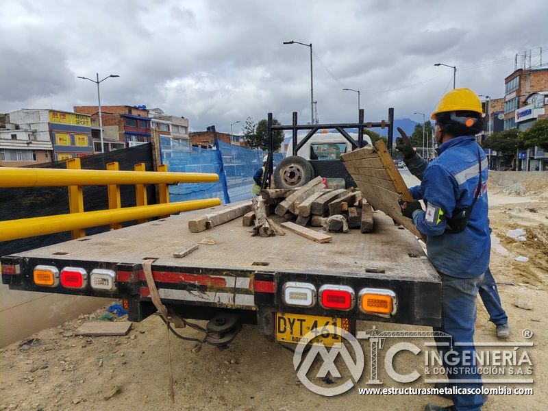 Observe la descarga organizada de madera y herramientas junto a barandas tubulares para puentes urbanos en Bogotá, Colombia. Montajes, Ingeniería y Construcción. MIC SAS.
