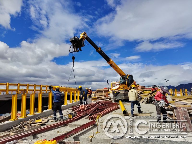 Eleve el tubo amarillo con dos eslingas y orientación manual hacia los postes que formarán el pasamanos en Bogotá, Colombia. Montajes, Ingeniería y Construcción. MIC SAS.