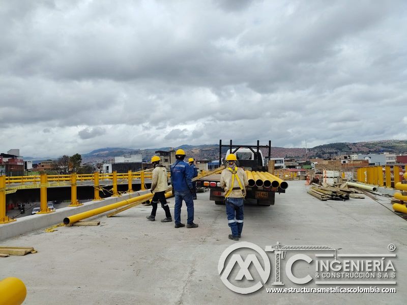 Observe la entrega de tubos amarillos y la distribución del personal entre postes para cerrar el puente en Bogotá, Colombia. Montajes, Ingeniería y Construcción. MIC SAS.