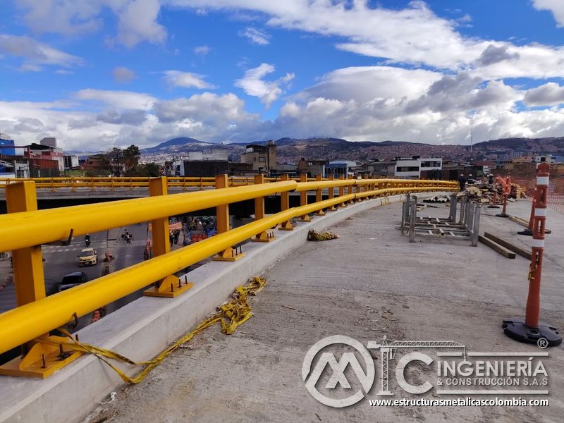 Recorra la curva del tablero protegida por barandas amarillas ancladas sobre el murete de concreto vial en Bogotá, Colombia. Montajes, Ingeniería y Construcción. MIC SAS.