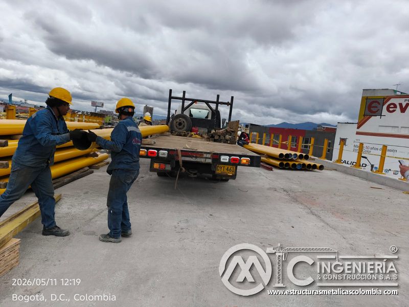 Aprecie la coordinación del equipo al manipular tubería amarilla destinada a la protección lateral vial en Bogotá, Colombia. Montajes, Ingeniería y Construcción. MIC SAS.