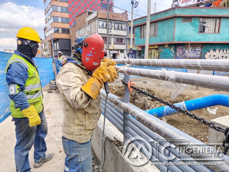 Controle la soldadura del tubo superior con careta y apoyo técnico, junto a la baranda del canal urbano en Bogotá, Colombia. Montajes, Ingeniería y Construcción. MIC SAS.