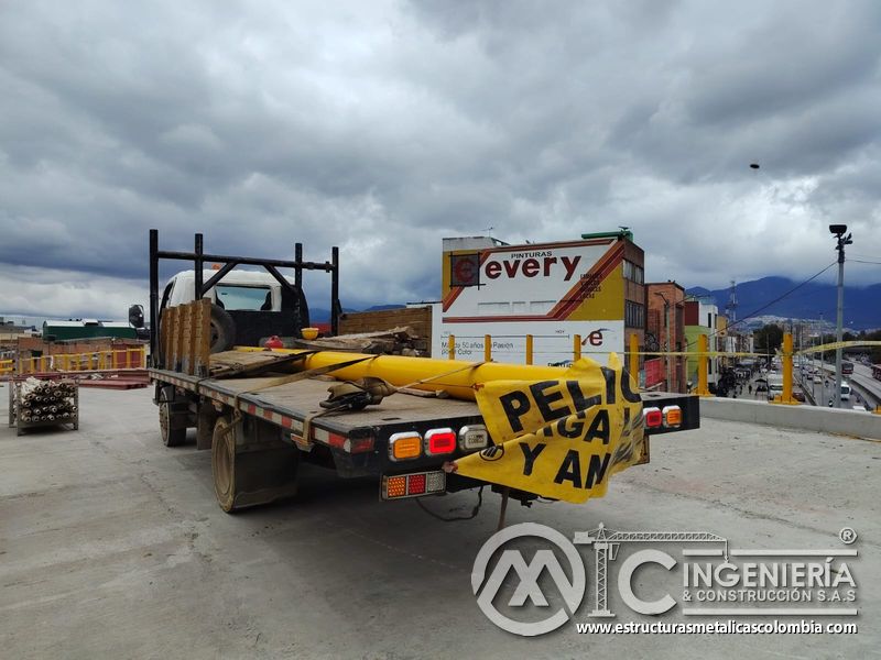 Observe el transporte de postes y tubos amarillos con señalización visible destinada a carga larga vial en Bogotá, Colombia. Montajes, Ingeniería y Construcción. MIC SAS.