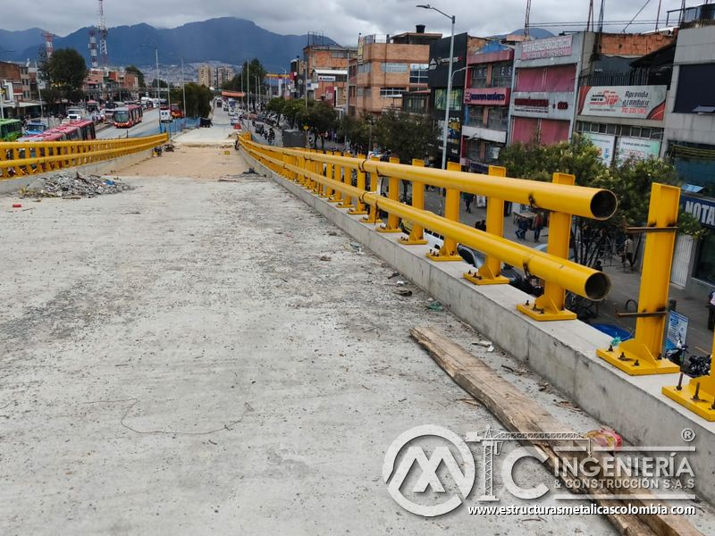 Observe la baranda amarilla anclada al murete que protege el descenso frente a la avenida urbana activa en Bogotá, Colombia. Montajes, Ingeniería y Construcción. MIC SAS.